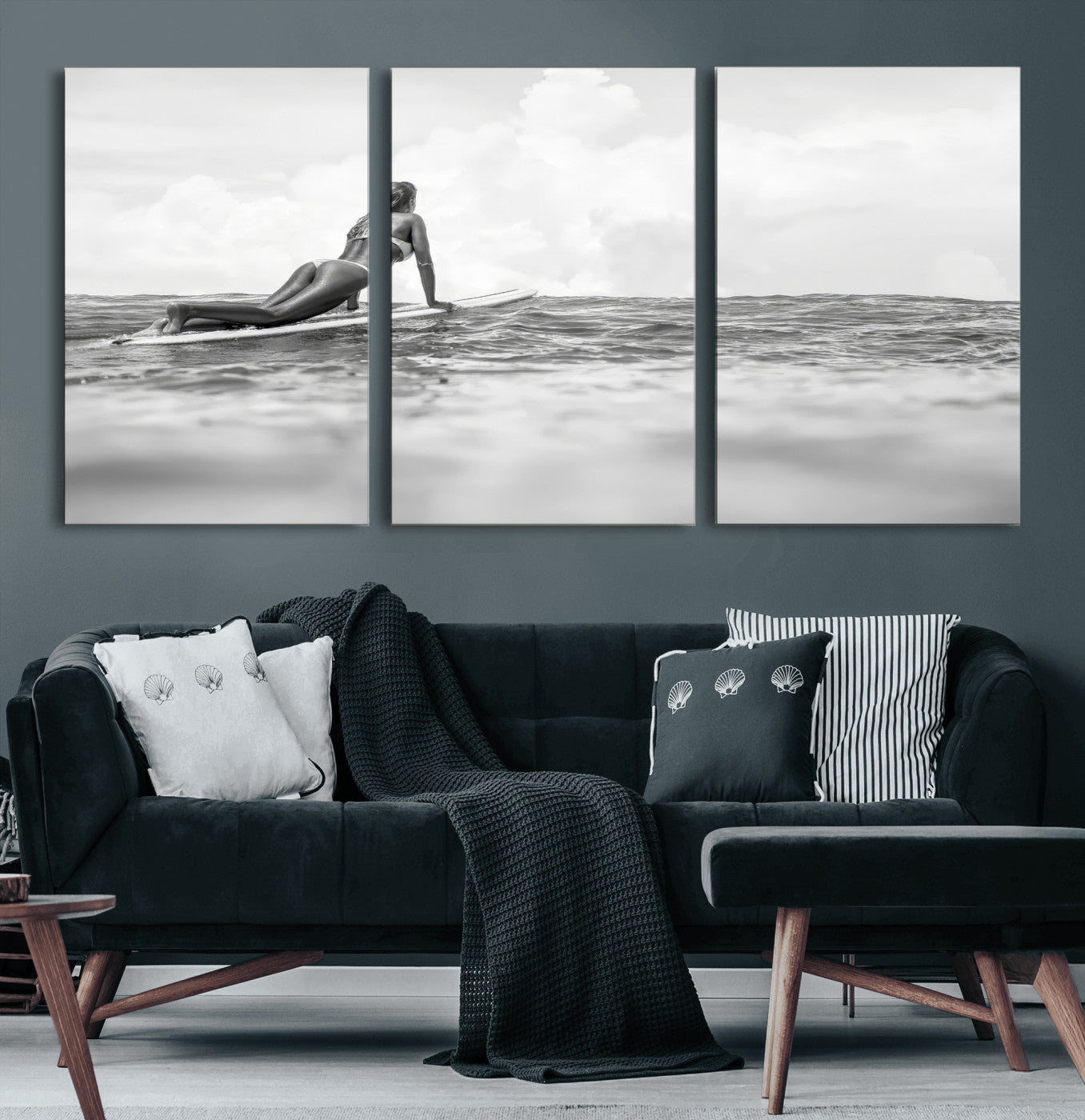 A black and white ocean scene featuring a surfer girl waiting on her board, gazing at the horizon, capturing a tranquil and adventurous coastal moment.