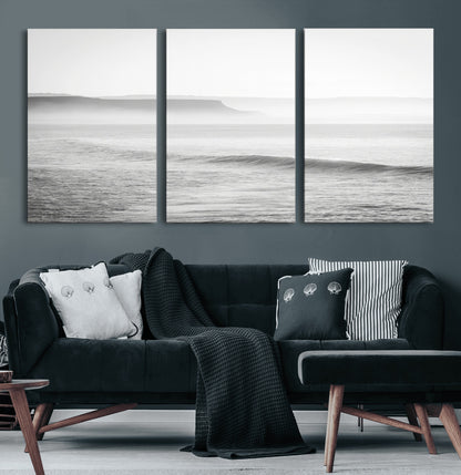 A black and white minimalist seascape featuring soft rolling waves and misty distant cliffs, creating a serene and timeless coastal atmosphere.