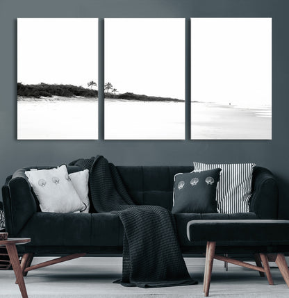 A black and white minimalist coastal scene with a vast open beach, distant palm trees, and a lone figure walking along the shoreline, evoking serenity and solitude.