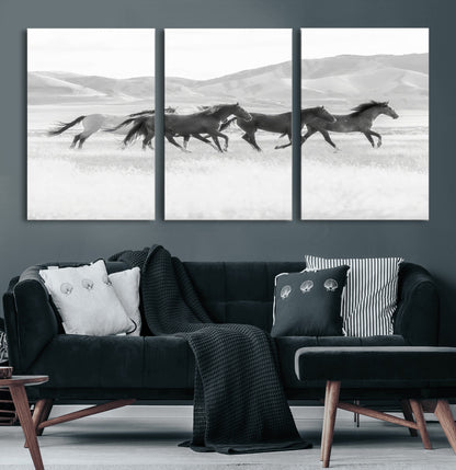 A black and white image of wild horses running freely across an open grassland, capturing the power and beauty of untamed nature in a rustic western setting.