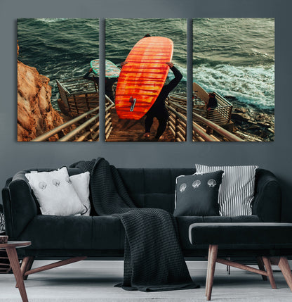 A surfer carrying a bold orange surfboard down a rugged staircase toward the ocean, bathed in golden hour light, capturing the energy of coastal adventure.