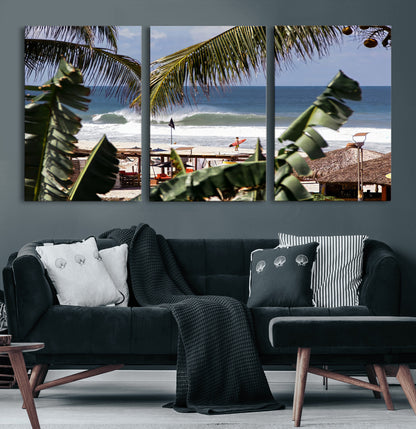 Canvas wall art of a tropical surf scene framed by palm trees, with a surfer on the shore and waves rolling in, ideal for beach-themed decor.