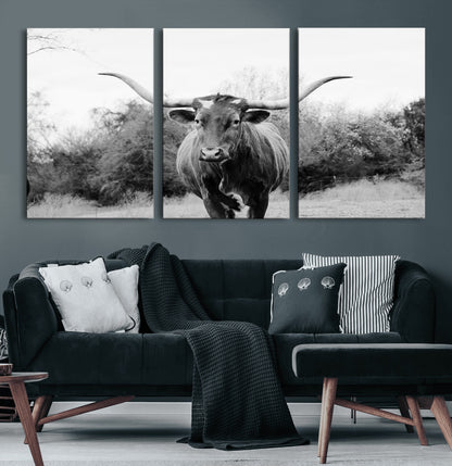 Black and white photo of a longhorn cow in a field, perfect for rustic farmhouse or western-themed interior wall decoration.