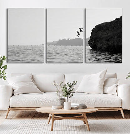Black and white canvas of two figures cliff jumping into the sea, captured with moody tones, ideal for modern coastal or adventure-themed home decor.   2/2