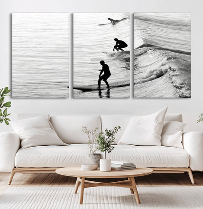 Black and white photo of surfers riding waves in a moody, high-contrast scene, ideal for modern coastal or surf-inspired home decor.