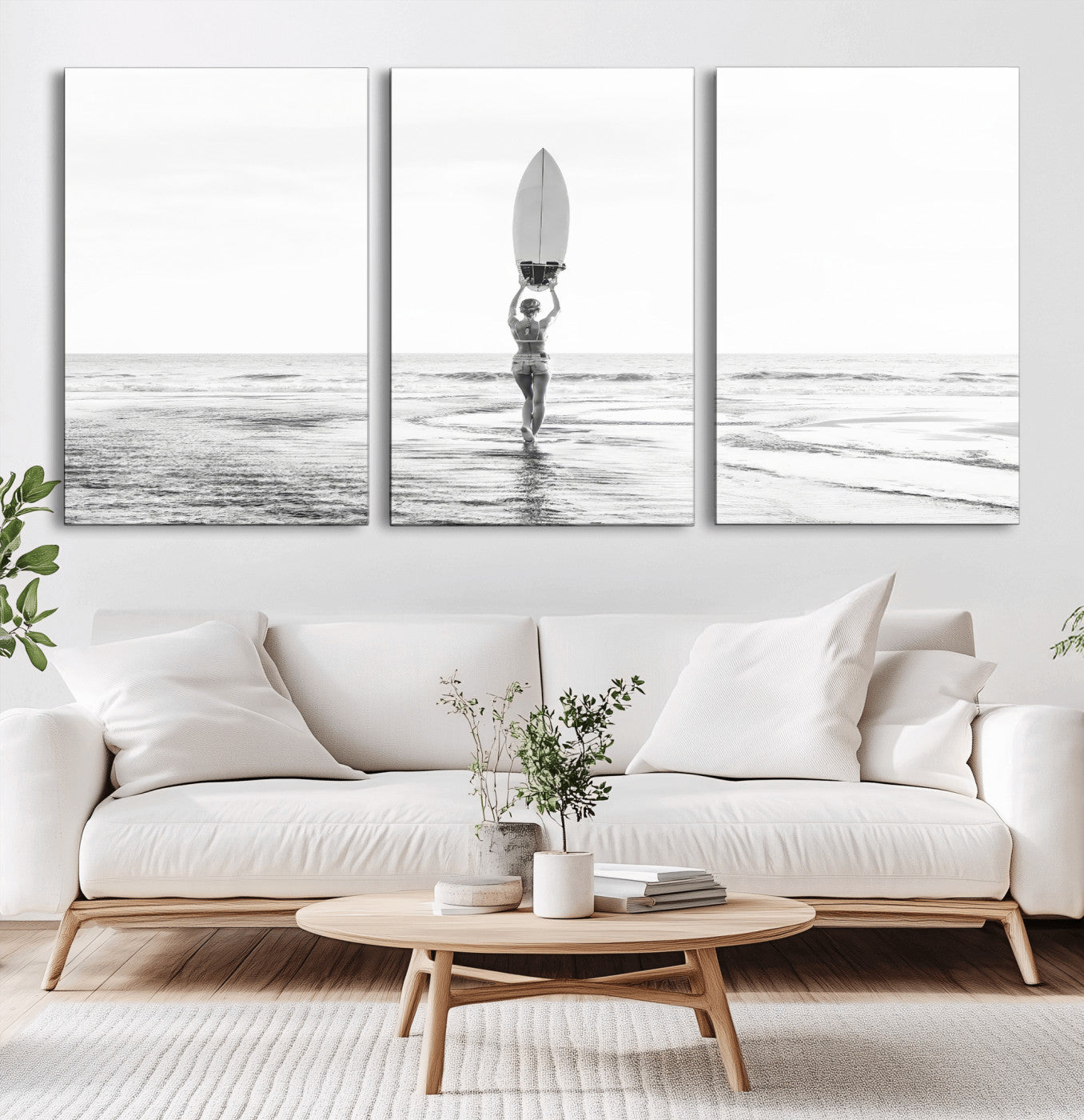 Black and white image of a female surfer holding a surfboard above her head while walking toward the ocean, creating a minimalist and bold coastal aesthetic.