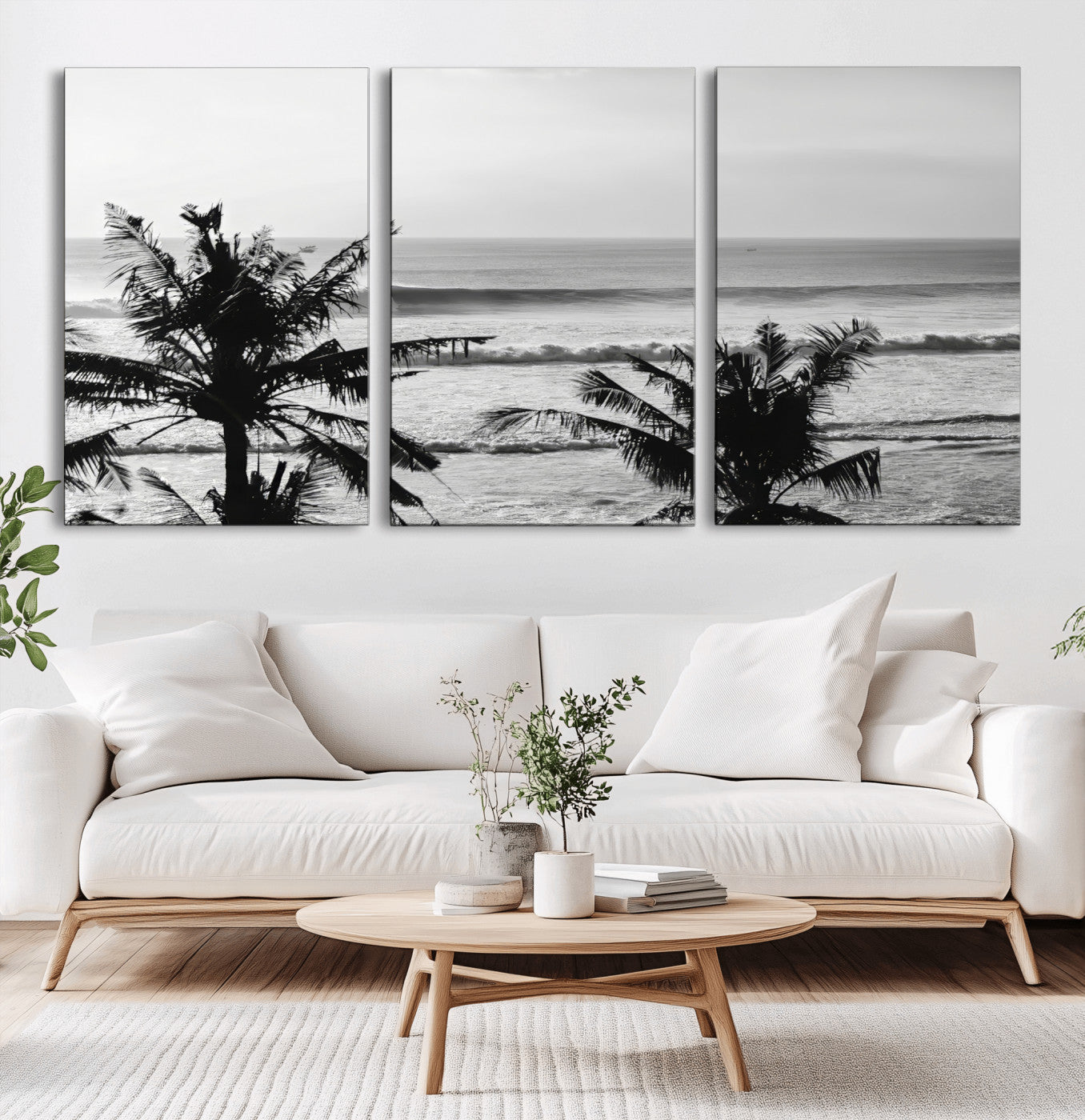 Black and white view of ocean waves crashing on a tropical coastline, framed by silhouetted palm trees under a vast, open sky.