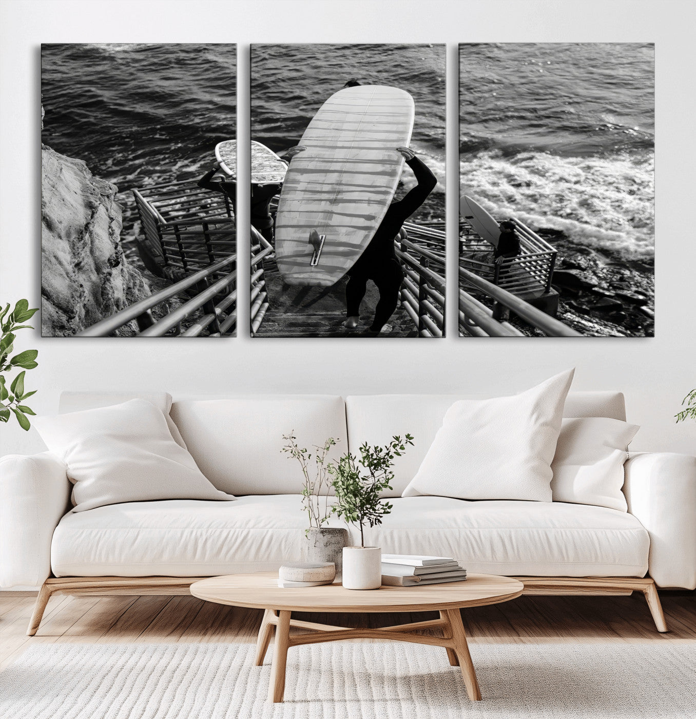 Black and white photo of surfers carrying boards down a rugged cliffside stairway, capturing a bold and adventurous coastal scene.