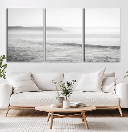 A black and white minimalist seascape featuring soft rolling waves and misty distant cliffs, creating a serene and timeless coastal atmosphere.