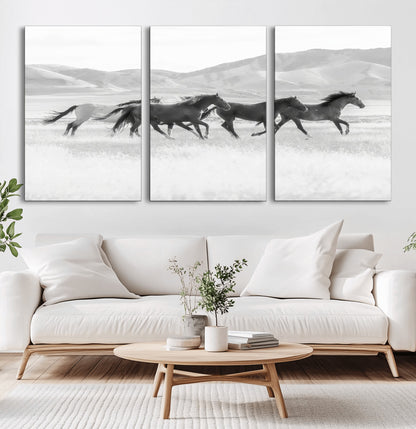 A black and white image of wild horses running freely across an open grassland, capturing the power and beauty of untamed nature in a rustic western setting.