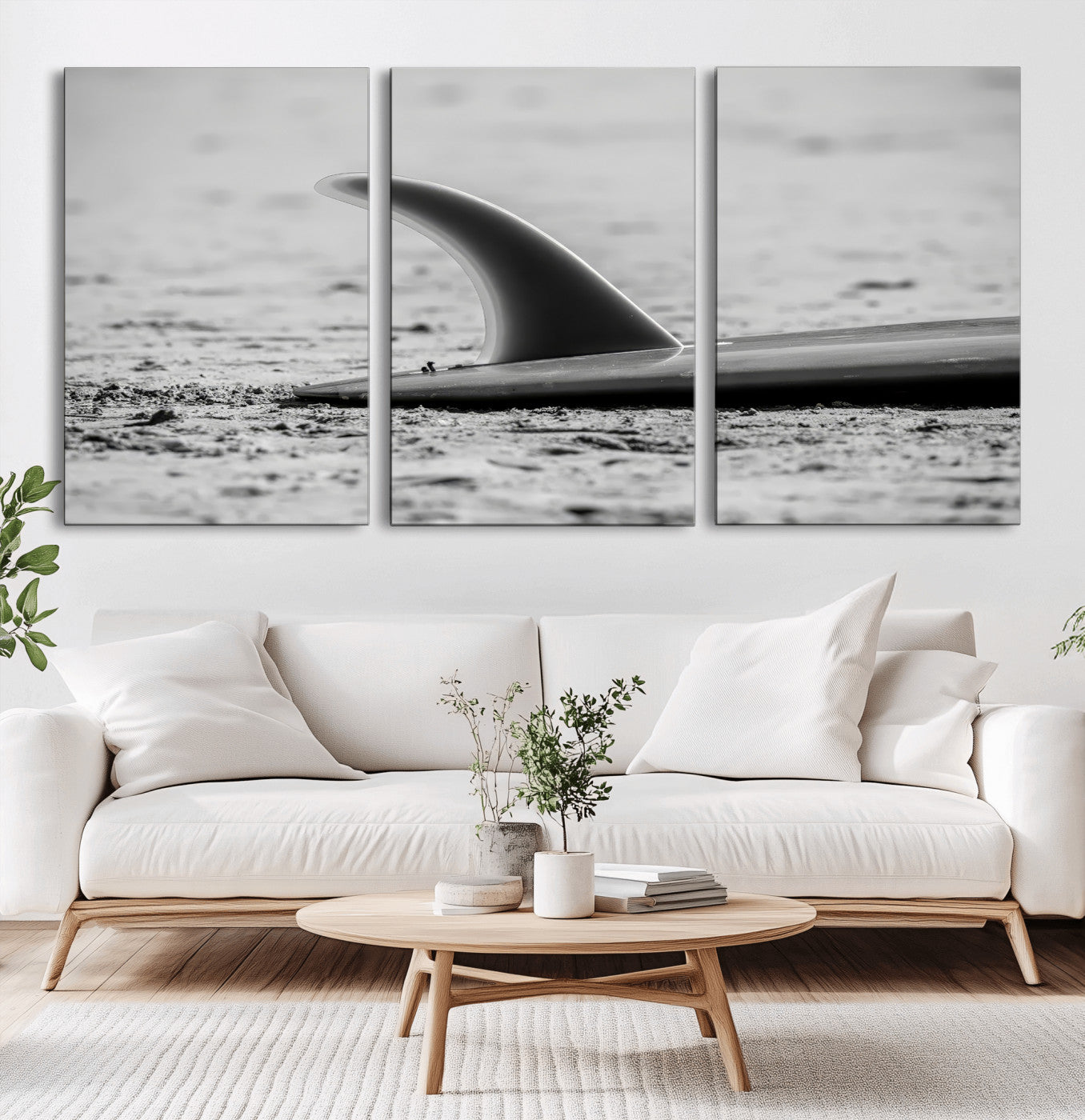 A black and white close-up of a surfboard fin resting on the sandy shore, highlighting minimalist beach aesthetics and classic surf culture.