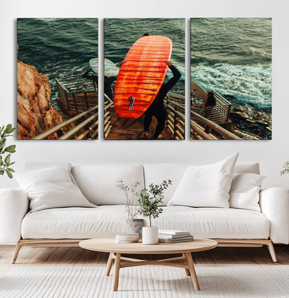 A surfer carrying a bold orange surfboard down a rugged staircase toward the ocean, bathed in golden hour light, capturing the energy of coastal adventure.