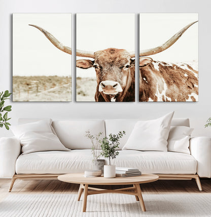A Texas longhorn bull with wide horns, standing in a dry field under soft light, ideal for rustic farmhouse or western-themed interiors.