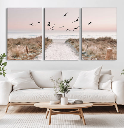 A peaceful coastal pathway leading to the ocean, with birds flying across a soft pastel sky, creating a calm and scenic beach atmosphere.