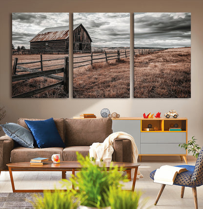 Framed canvas of a rustic barn under a moody sky with weathered fence and dark fields, ideal for farmhouse or rural-style wall decor.