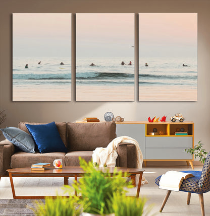 Dreamy photo of surfers waiting on soft pastel waves under a pink sunset sky, ideal for soft coastal minimalist or serene ocean-themed home decor.
