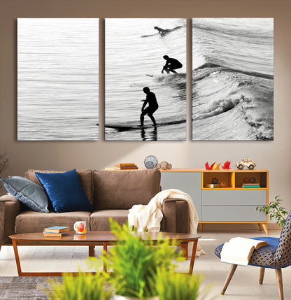 Black and white photo of surfers riding waves in a moody, high-contrast scene, ideal for modern coastal or surf-inspired home decor.
