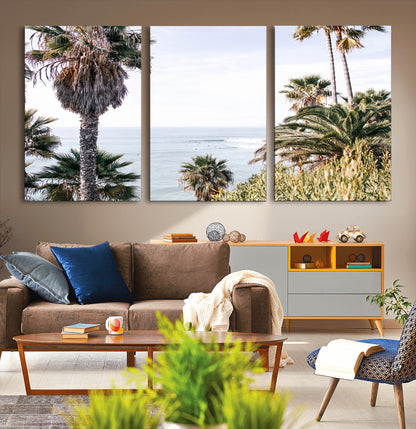Scenic coastal view with tall palm trees overlooking a calm ocean, soft blue waves, and surfers in the distance, creating a peaceful tropical vibe.