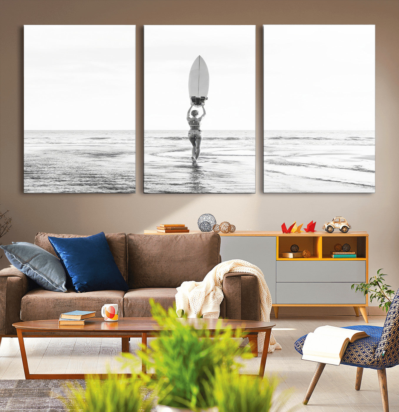 Black and white image of a female surfer holding a surfboard above her head while walking toward the ocean, creating a minimalist and bold coastal aesthetic.