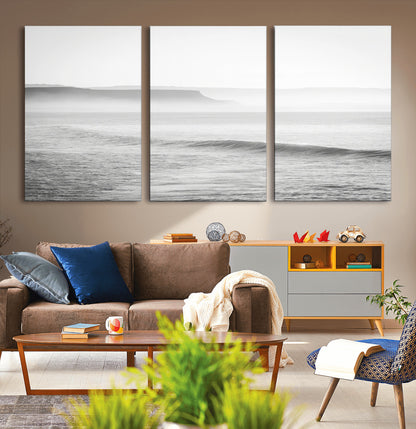 A black and white minimalist seascape featuring soft rolling waves and misty distant cliffs, creating a serene and timeless coastal atmosphere.