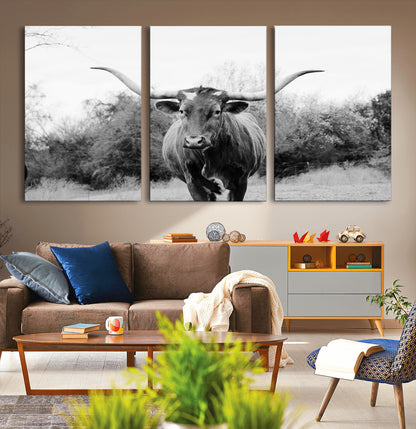 Black and white photo of a longhorn cow in a field, perfect for rustic farmhouse or western-themed interior wall decoration.