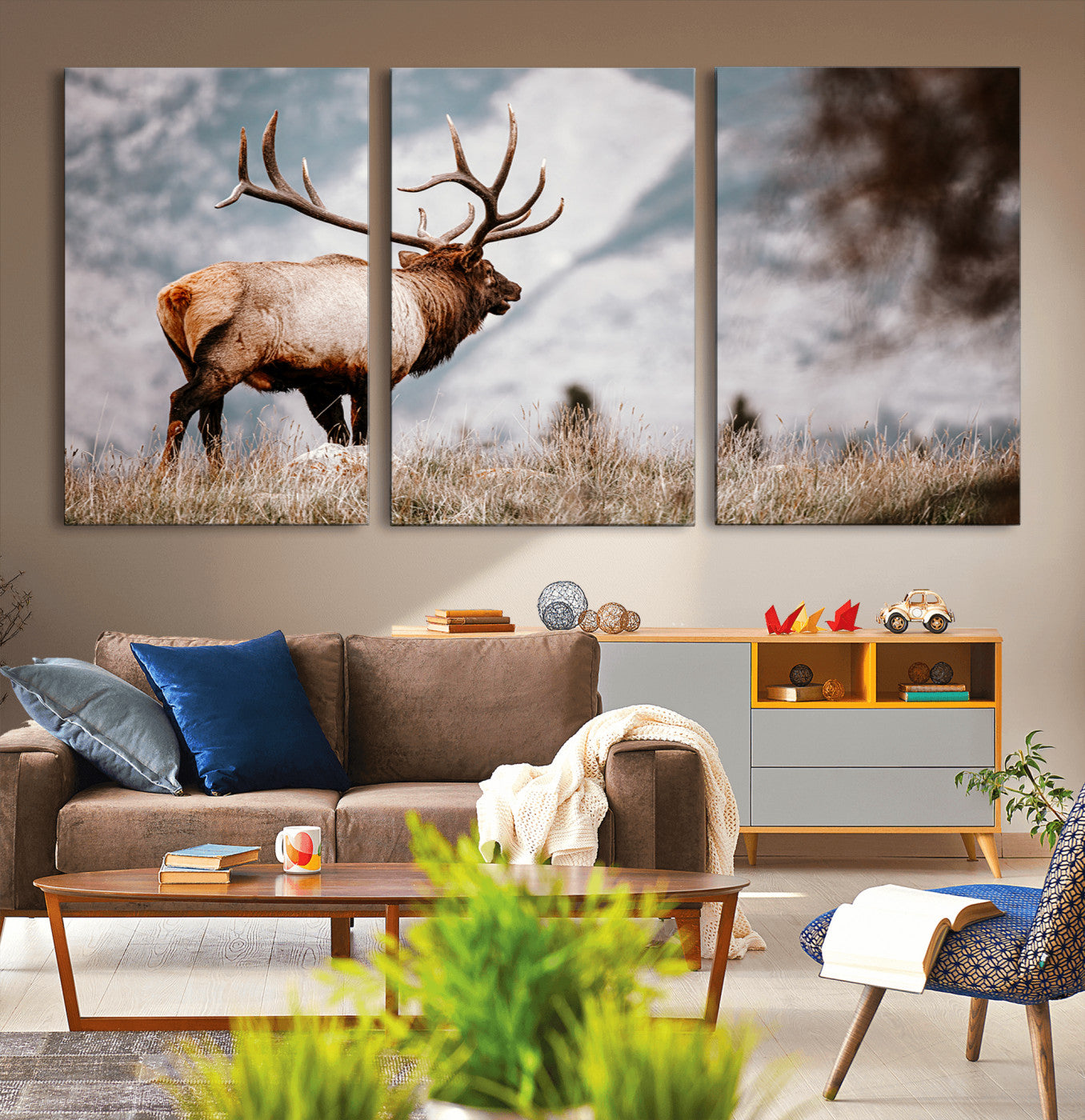Majestic elk with large antlers standing in grass with snowy mountains in background, perfect for rustic cabin or lodge style decor.