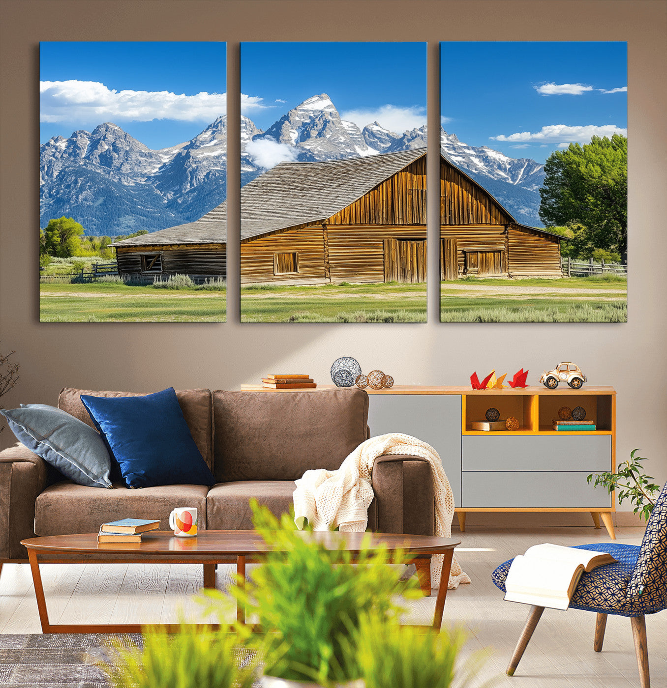 A rustic wooden barn sits in front of towering mountain peaks under a clear blue sky, perfect for farmhouse or cabin style interiors.