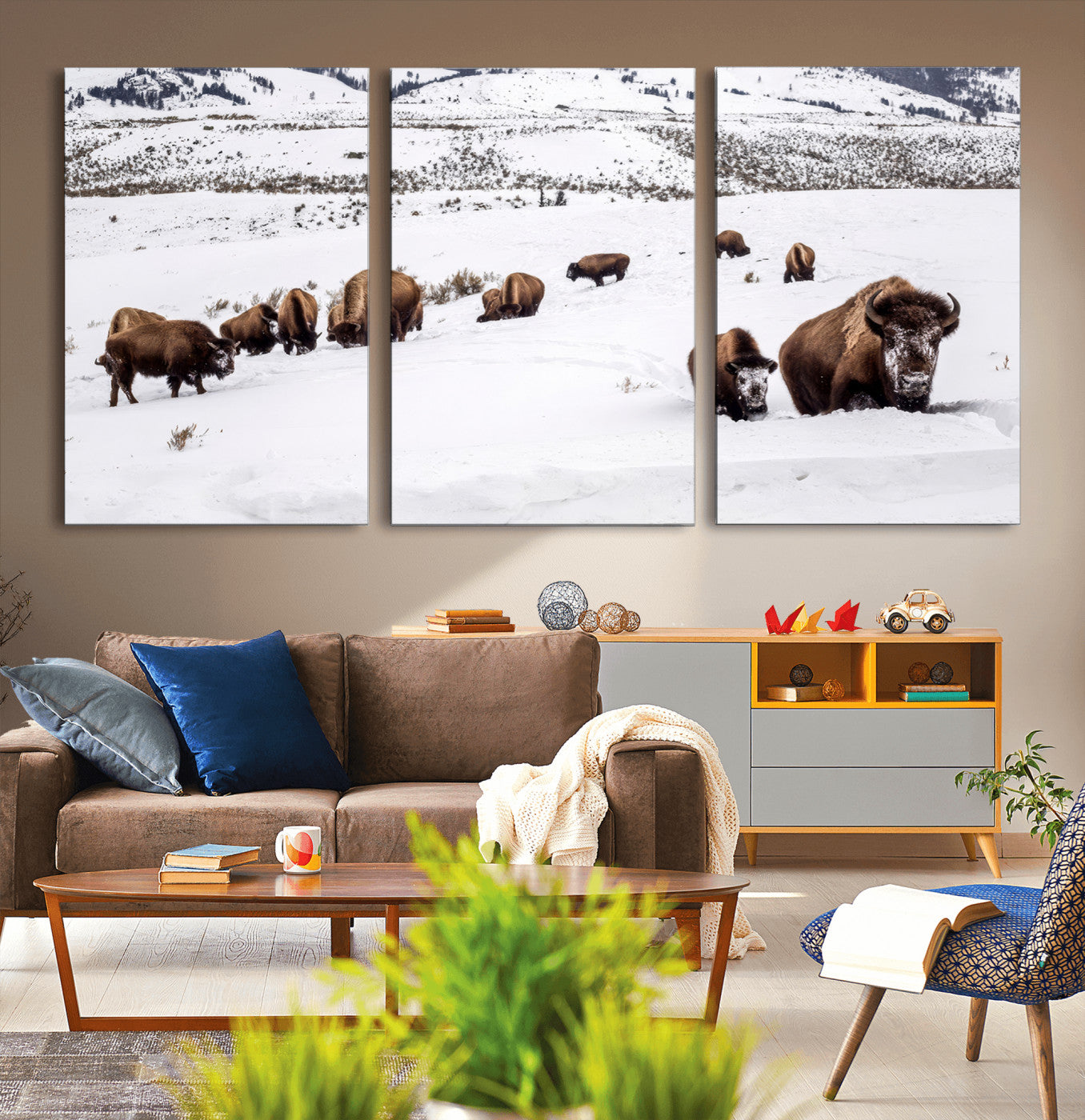 A herd of bison walking through deep snow in a mountain valley, perfect for rustic, cabin or western-themed wall decor.