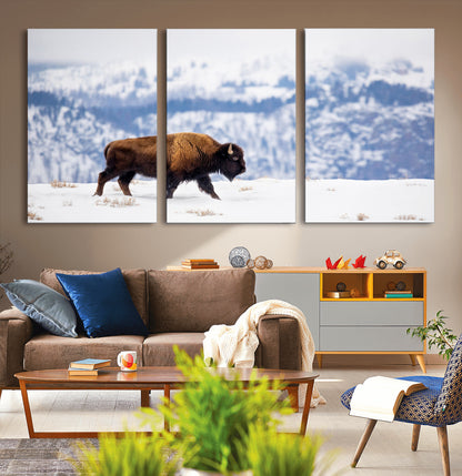 A lone bison walks across snowy ground with blue-toned mountain range behind, ideal for rustic or western farmhouse interiors.