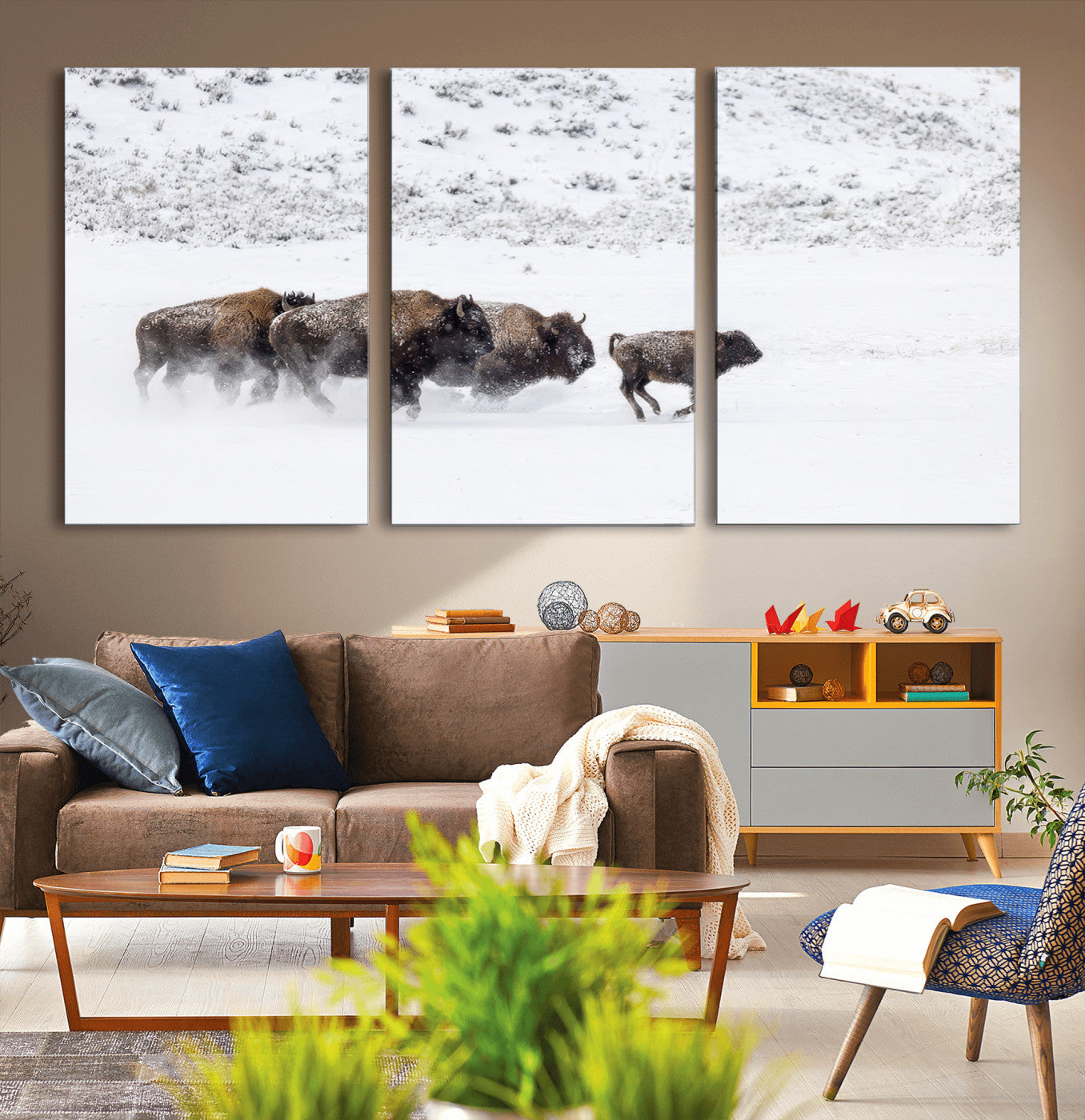 Bison herd running through a snowy open field with mountain backdrop, perfect for rustic or western-themed wall decoration.