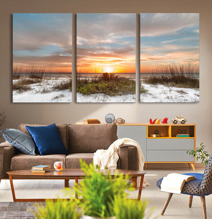 A tranquil beach scene featuring golden sunset hues over the water, with grasses in the foreground and a peaceful, serene atmosphere.