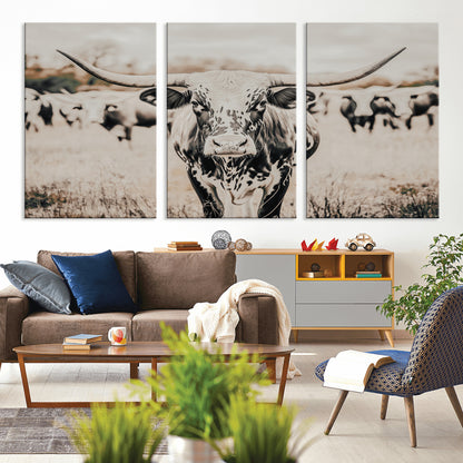 Canvas of a speckled Texas longhorn standing boldly in a field with a herd behind, perfect for rustic western or farmhouse wall decor.