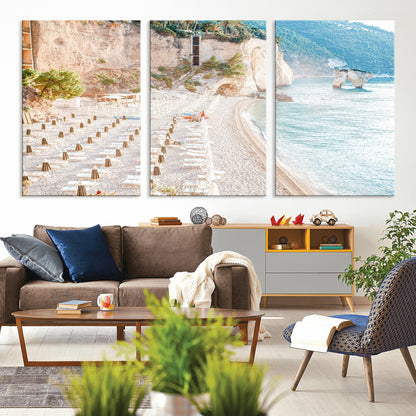 Wall art of a calm Mediterranean beach with rows of sun loungers and umbrellas in soft pastel tones, perfect for light coastal or vacation-themed decor.