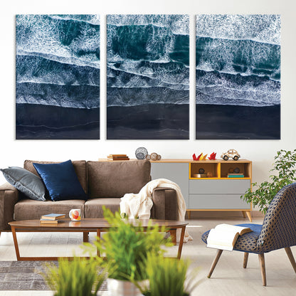 Canvas of aerial ocean waves crashing onto a black sand beach in moody tones, ideal for modern coastal or minimalist home decor.