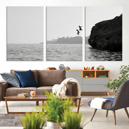 Black and white canvas of two figures cliff jumping into the sea, captured with moody tones, ideal for modern coastal or adventure-themed home decor.   2/2