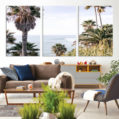 Scenic coastal view with tall palm trees overlooking a calm ocean, soft blue waves, and surfers in the distance, creating a peaceful tropical vibe.