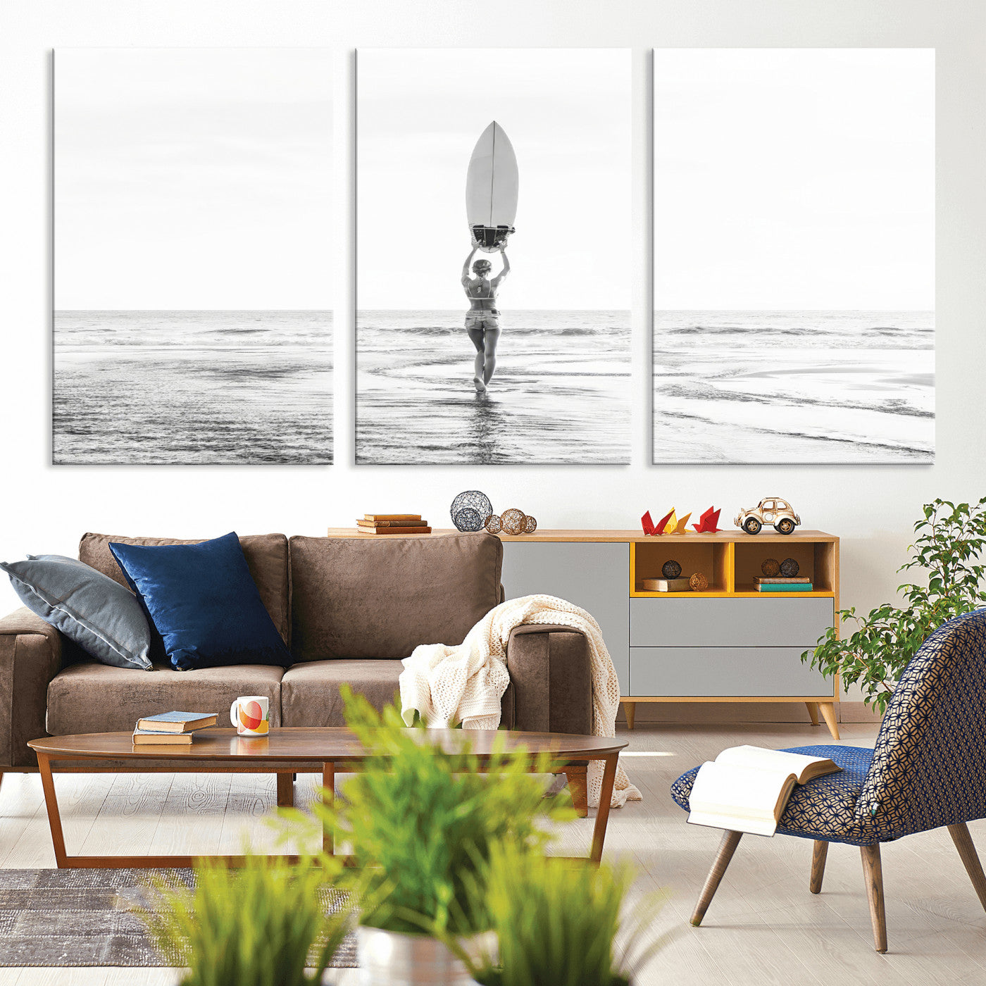 Black and white image of a female surfer holding a surfboard above her head while walking toward the ocean, creating a minimalist and bold coastal aesthetic.