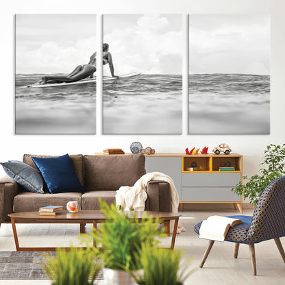 A black and white ocean scene featuring a surfer girl waiting on her board, gazing at the horizon, capturing a tranquil and adventurous coastal moment.