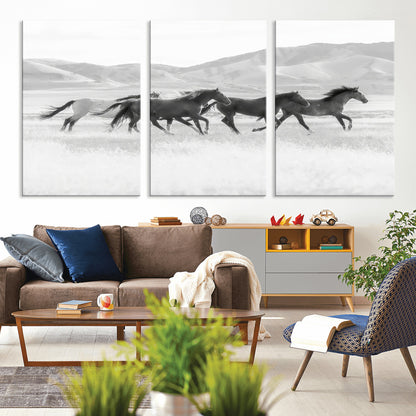 A black and white image of wild horses running freely across an open grassland, capturing the power and beauty of untamed nature in a rustic western setting.