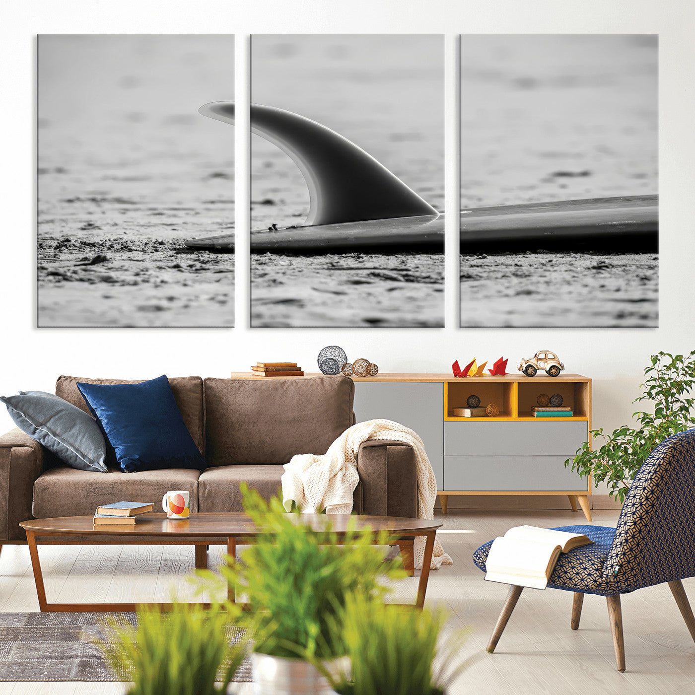 A black and white close-up of a surfboard fin resting on the sandy shore, highlighting minimalist beach aesthetics and classic surf culture.