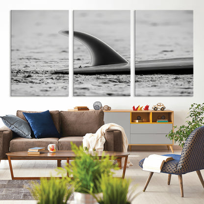 A black and white close-up of a surfboard fin resting on the sandy shore, highlighting minimalist beach aesthetics and classic surf culture.