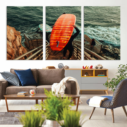 A surfer carrying a bold orange surfboard down a rugged staircase toward the ocean, bathed in golden hour light, capturing the energy of coastal adventure.