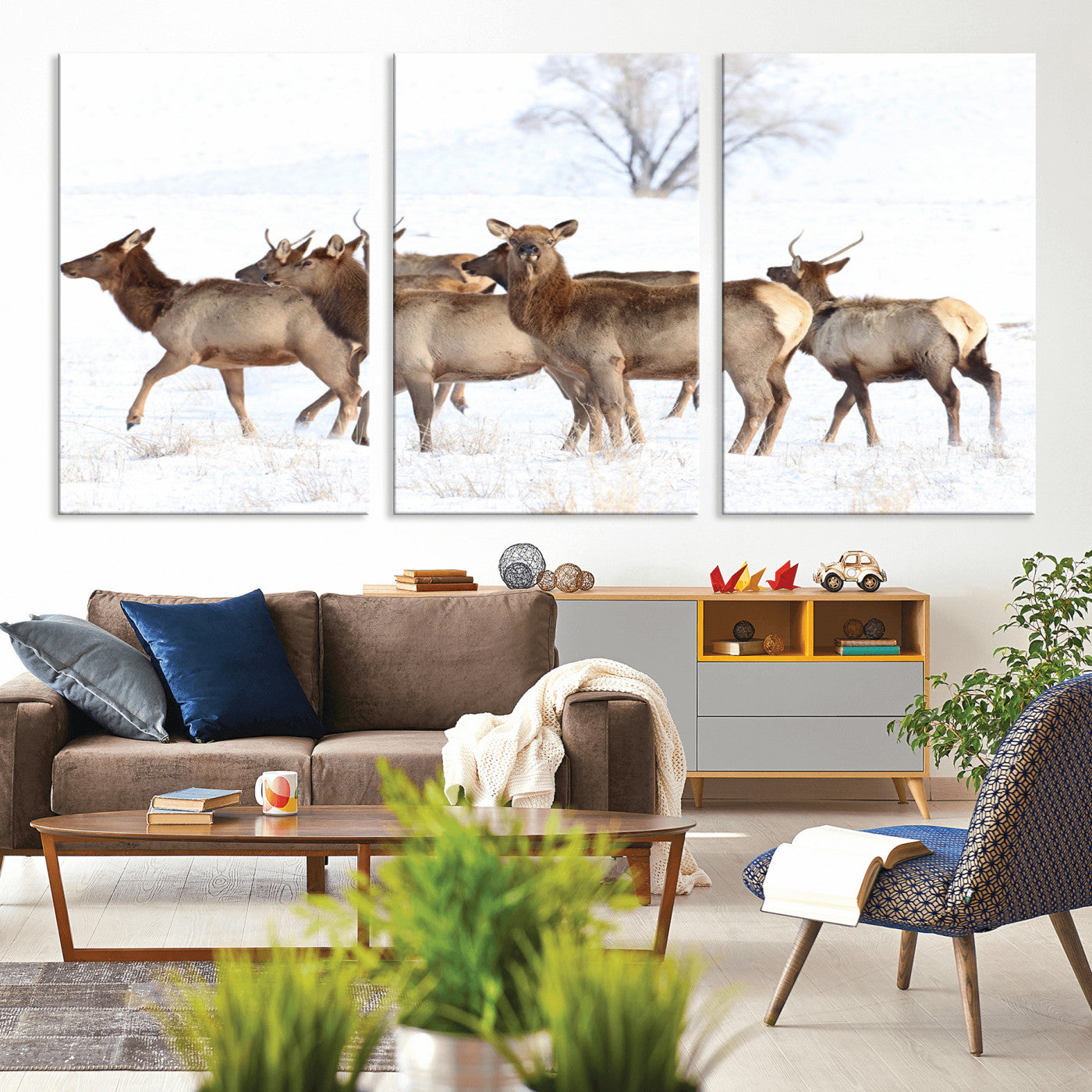 A group of elk standing on snowy terrain with a tree in the background, perfect for rustic or lodge-style winter wall decor.