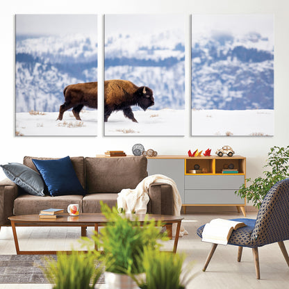 A lone bison walks across snowy ground with blue-toned mountain range behind, ideal for rustic or western farmhouse interiors.