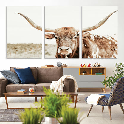 A Texas longhorn bull with wide horns, standing in a dry field under soft light, ideal for rustic farmhouse or western-themed interiors.